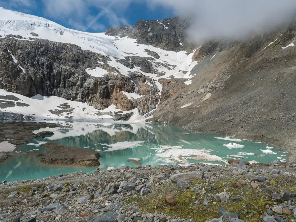 summer view of the Sulzenauferner Glacier and turquoise glacial lake and waterfall from melting ice. Stubai Alps, Austria