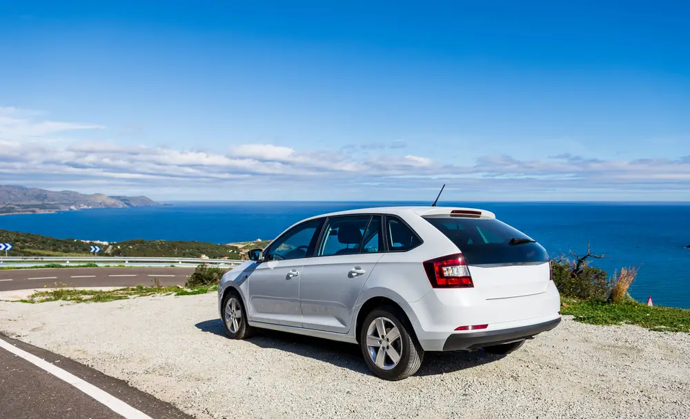 A car of white color, the station wagon travels along a dirt road, stony roads along the coastline in the mountains near the coast of the Costa Brava of the Mediterranean Sea in Spain, Catalonia.