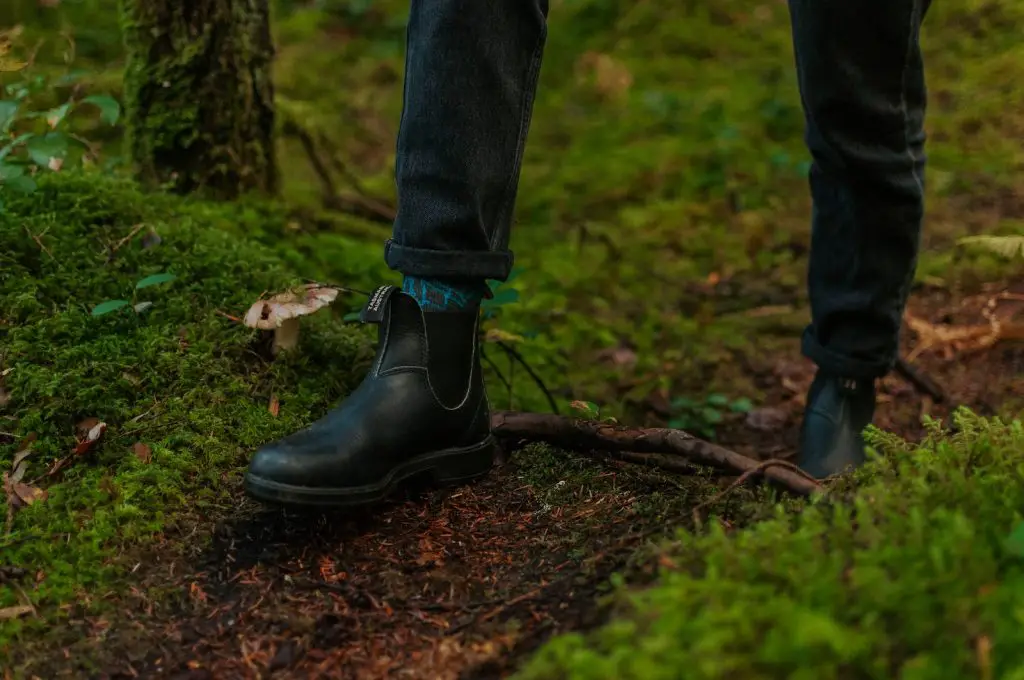 a person in black boots standing in the grass