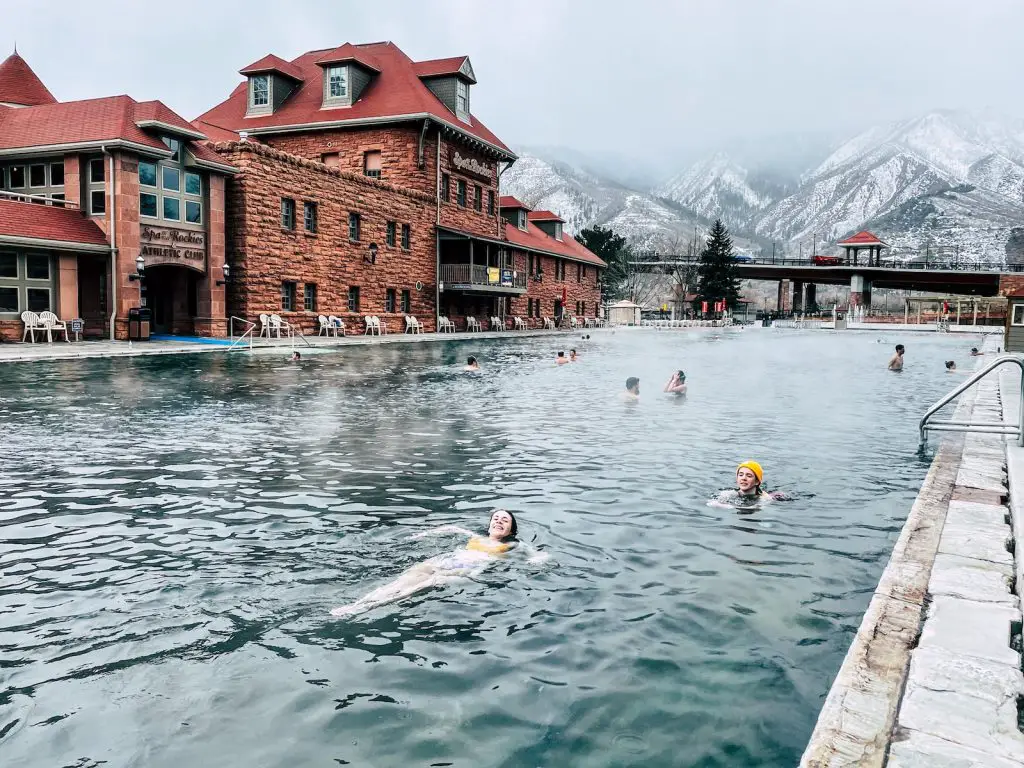 people swimming on the river near the red and brown concrete building during daytime