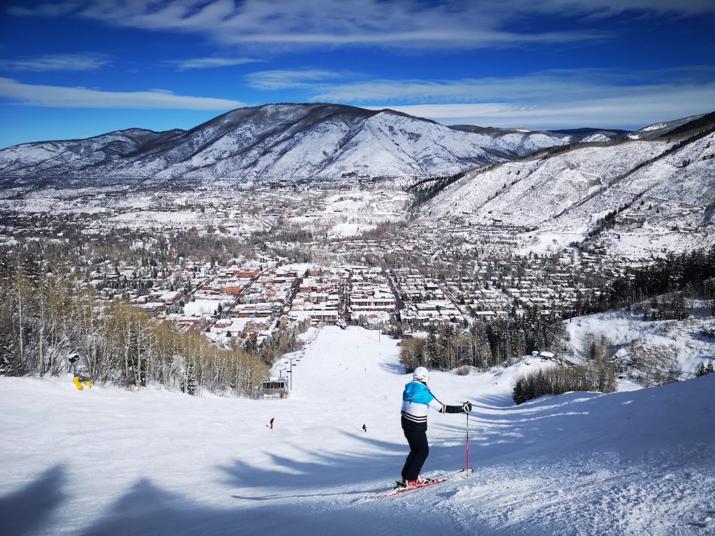 person in red jacket and blue pants riding ski blades on snow covered ground during daytime, Aspen, Colorado